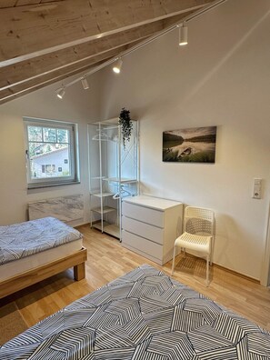 A bedroom with a bed, a desk, a chair, a wardrobe, and a window.