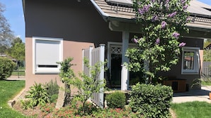 A house with a front porch, a small garden with flowers, and a visible garage door.