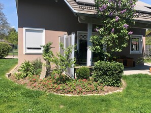 A house with a front porch, a small garden with flowers, and a visible garage door.