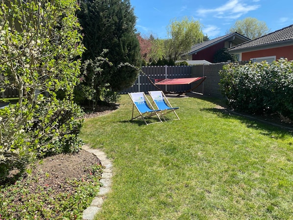 A backyard with a hammock, a lawn, and a red building.