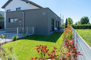 A modern building with a flat roof, a fenced yard, and a well-maintained lawn. - Murner See Lodge – Modern Holiday Apartment at the Lake "Murner See" / Bavaria (Wackersdorf)