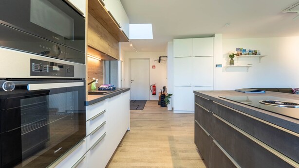 Una cucina moderna con forno integrato, microonde e frigorifero. Un piano di lavoro in legno e uno schienale.