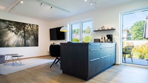 Una cucina moderna con un'ampia finestra, un'isola nera e un'area pranzo con un tavolo e sedie.