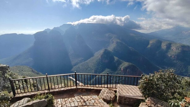 A stone bench and railing overlooking a mountainous landscape.
