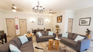 A living room with two sofas, a chandelier, a dining table, and a fireplace.