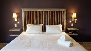 A neatly made bed with pillows, a wooden headboard, bedside lamps, and a folded towel on the bed.