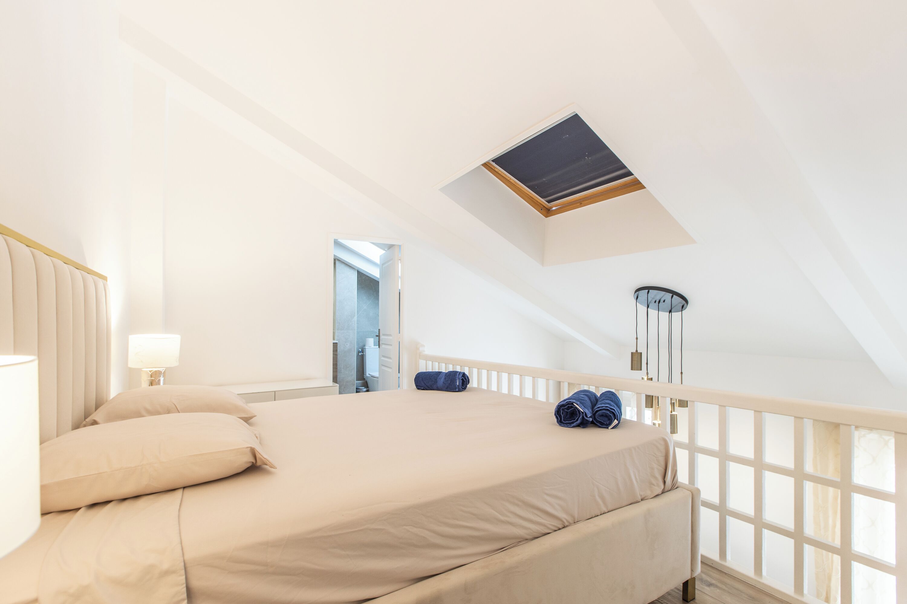 A bedroom with a bed, a nightstand, a lamp, a ceiling fan, and a window with a view.