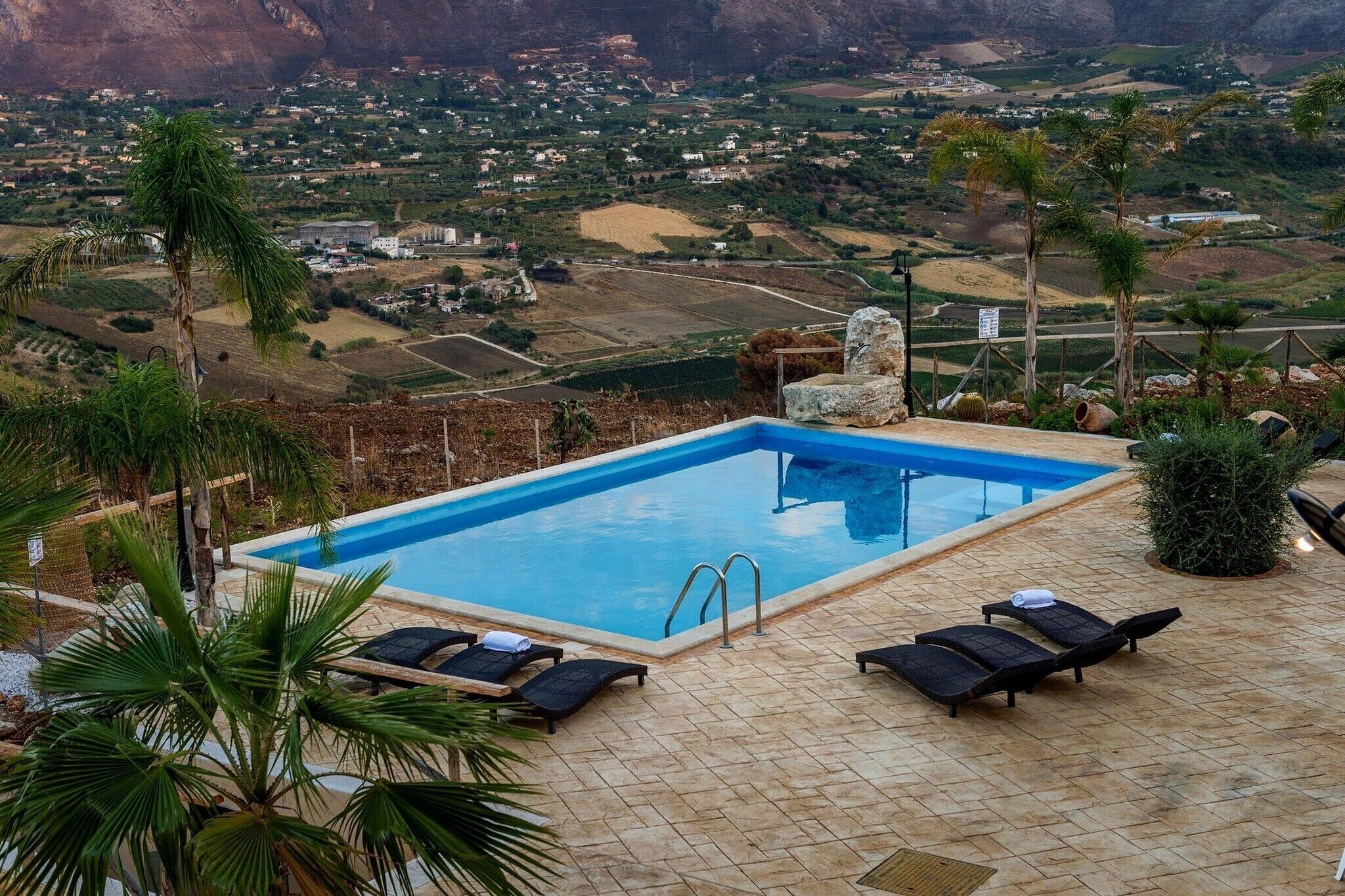 A swimming pool with lounge chairs and a view of a valley.