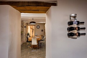 A dining area with a wooden table and chairs, a wall-mounted wine rack, and a rustic stone wall. - Villa in Sicily with private pool (Castellammare del Golfo)