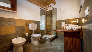 Un bagno con doccia, bidet, toilette e mobile lavabo in legno.