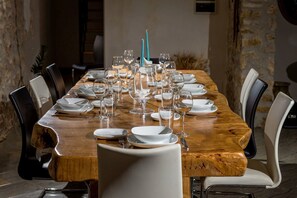 Una larga mesa de comedor de madera dispuesta con platos blancos, vasos y un centro de mesa con velas color turquesa.