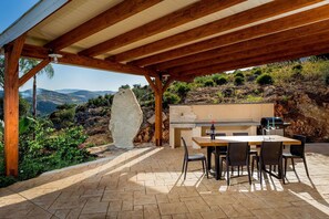 An outdoor patio with a wooden pergola, a barbecue grill, and a dining table with chairs. - Villa in Sicily with private pool (Castellammare del Golfo)