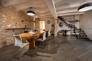 Ein Essbereich mit Holztisch und Stühlen, einer Steinwand, einer Treppe und einem modernen Lichtarmaturen.