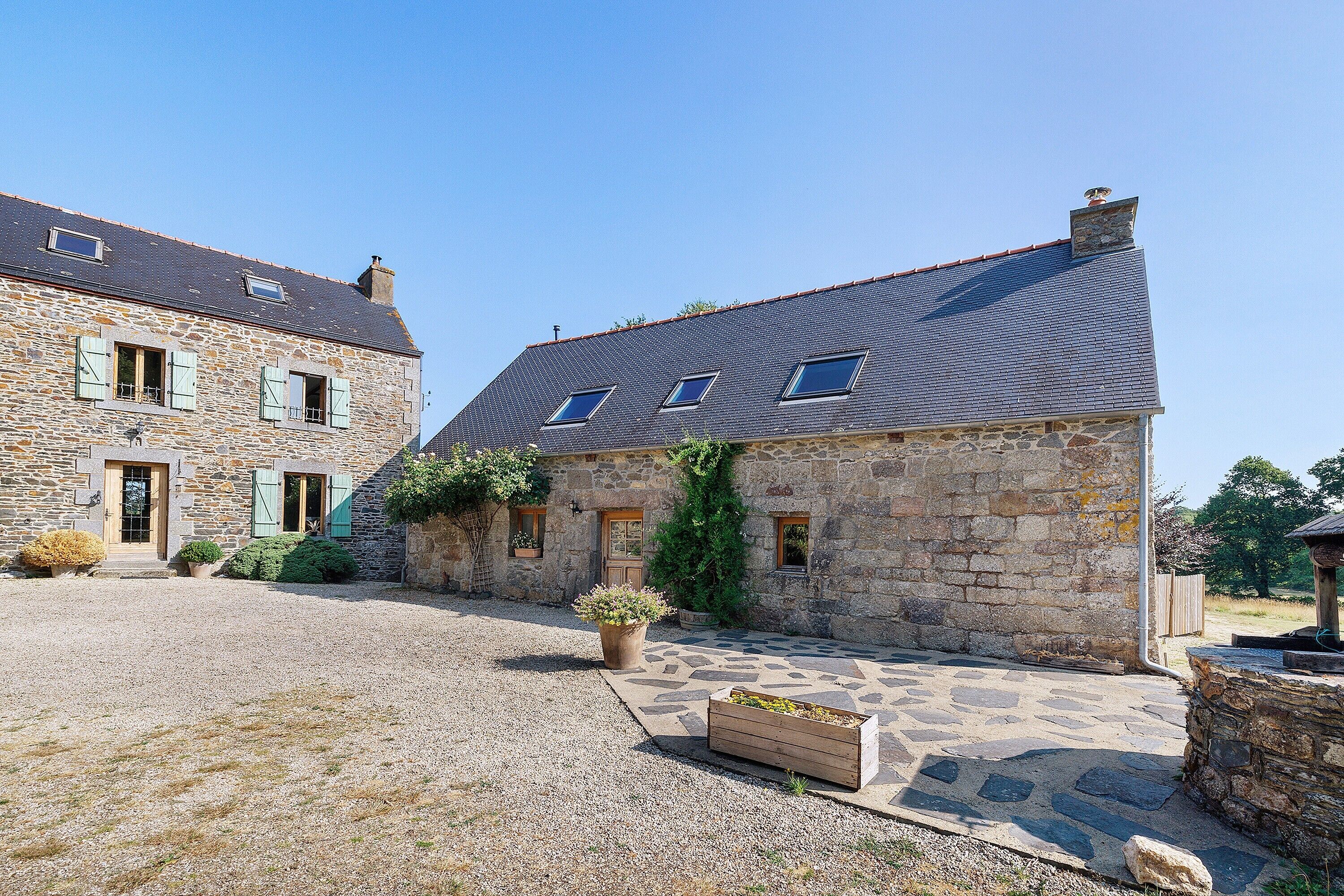 A stone building with a gravel courtyard, a wooden door, and a window with shutters.
