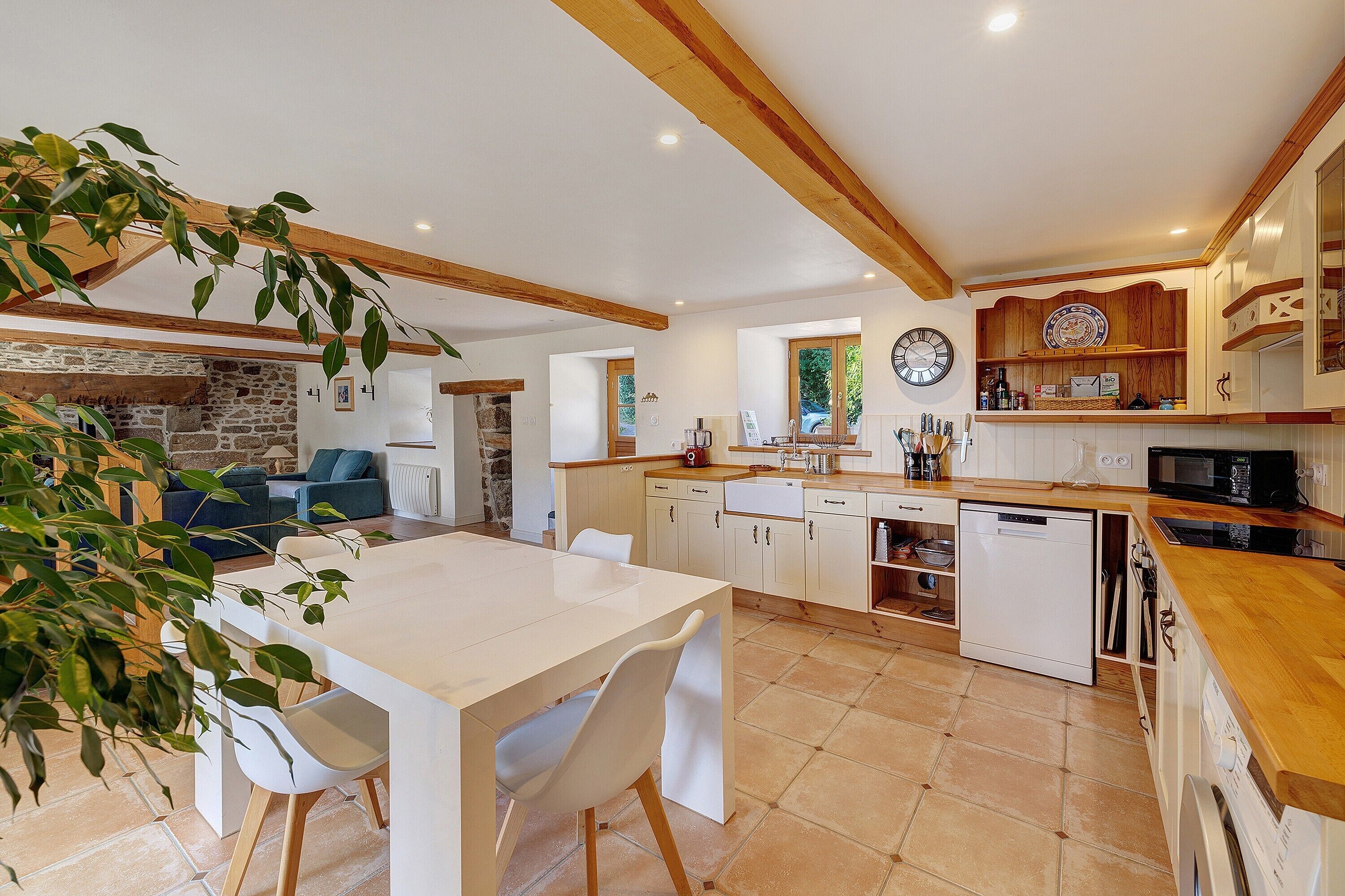 Une cuisine moderne avec des meubles blancs, un plan de travail en bois et un lave-vaisselle encastré.