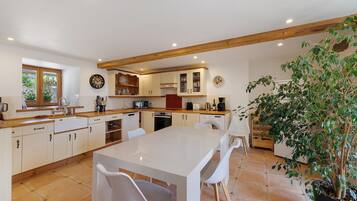 A modern kitchen with a central island, wooden beams, and a potted plant.