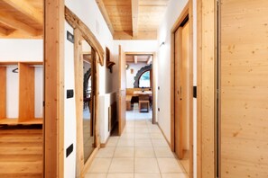 A hallway with wooden walls and a tiled floor leading to a room with a window and a door.