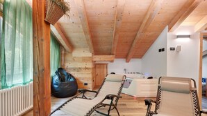 Un interior de madera con dos sillones reclinables, un asiento de tierno negro, un radiador blanco y un techo de madera.