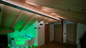 Una habitación con techo de madera, una bañera con iluminación verde y suelo de madera.