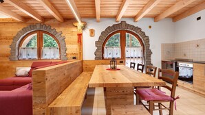 Interior de madera con una gran mesa de comedor, bancos y un sofá.