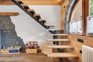 A wooden staircase with a stone wall, wooden benches, and a radiator.