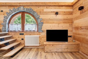 A wooden interior with a stone arch window, a flat-screen TV, and wooden benches.