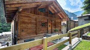 Una cabaña de madera con un porche de madera y un muro de piedra.