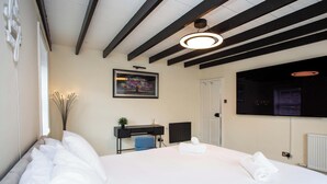 A hotel room with a bed, a desk, a chair, a picture on the wall, and a window. - Vacant Nests  Relaxing Rural Cottage  Scenic (Wearhead)