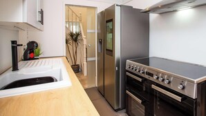 A modern kitchen with a stainless steel refrigerator, a built-in oven, and a sink. - Vacant Nests  Relaxing Rural Cottage  Scenic (Wearhead)