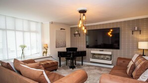 A living room with a sofa set, a piano, a flat-screen TV, and a fireplace. - Vacant Nests  Relaxing Rural Cottage  Scenic (Wearhead)