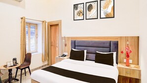 Una camera d'albergo con un letto, un comodino, una sedia, una finestra e un'opera d'arte appesa al muro.