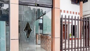 L'ingresso di un edificio con una porta in vetro, un cancello in metallo e un muro in mattoni.
