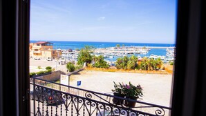 A balcony with a view of a marina, boats, and a beach. - La Casa della Zia (San Nicola l'Arena)
