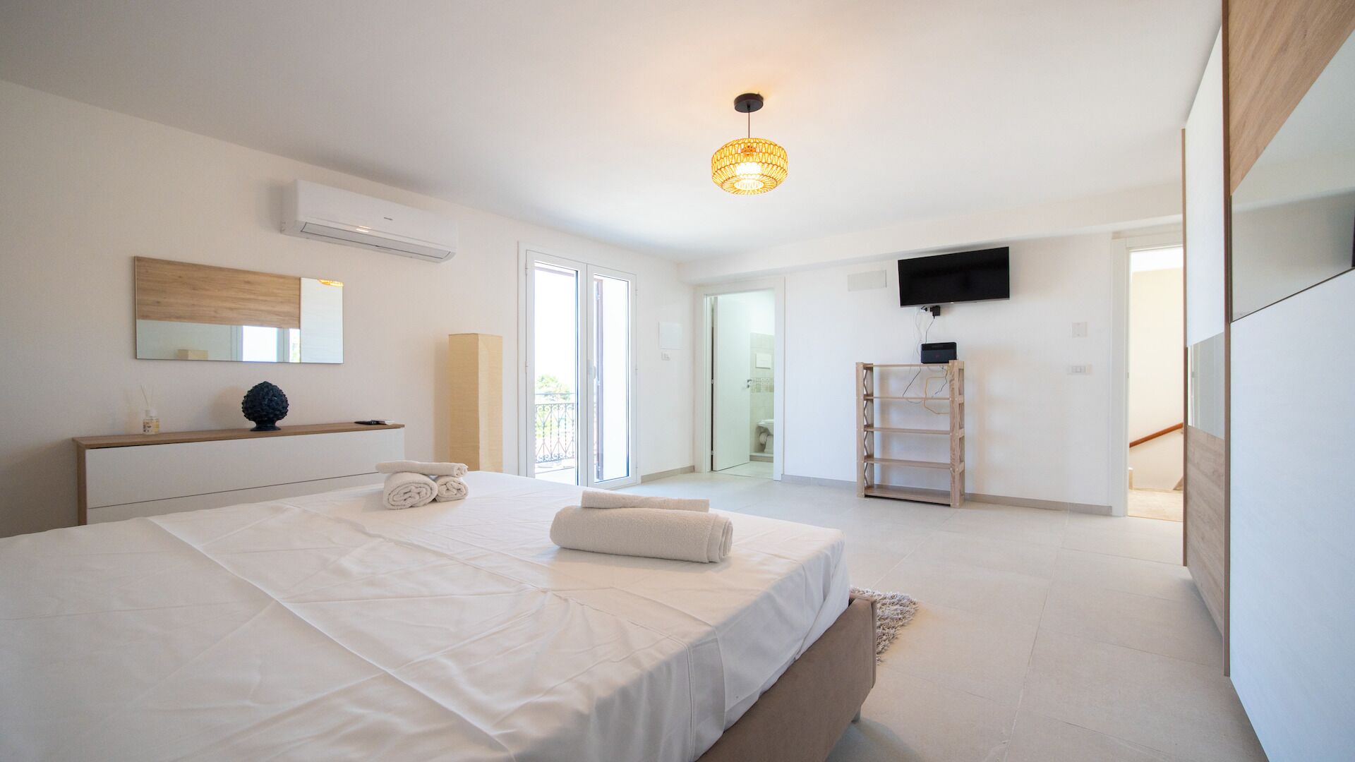 Una camera da letto moderna con un grande letto, una TV a schermo piatto e un lampadario.
