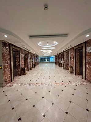 A hotel corridor with marble flooring, doors, and a ceiling with recessed lighting. - Vivian Al-Shasha Hotel (Makkah)
