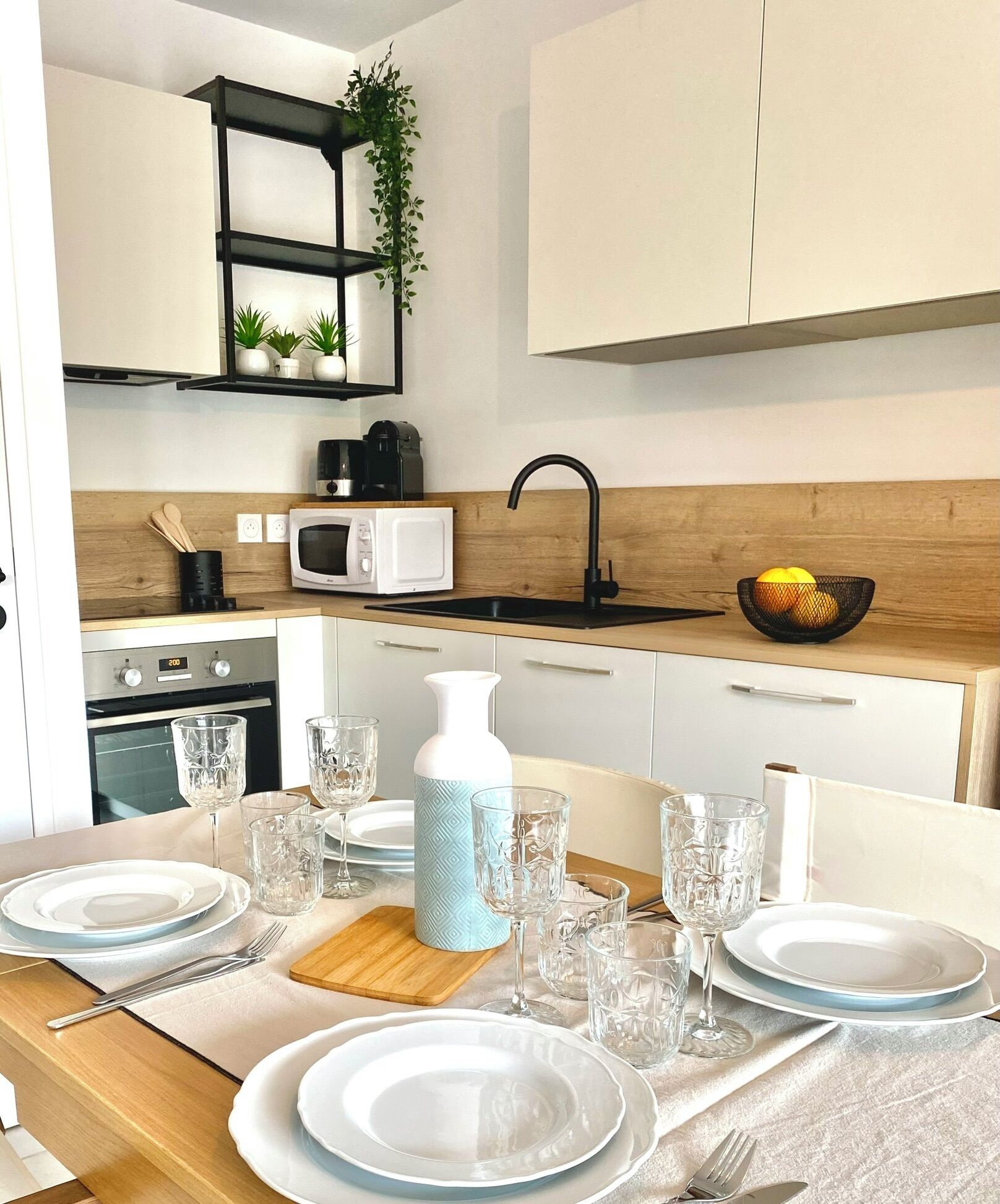 A modern kitchen with a wooden countertop, a black sink, a white microwave, and a black coffee maker.