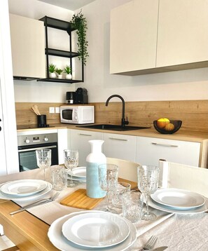 A modern kitchen with a wooden countertop, a black sink, a white microwave, and a black coffee maker. - The Ondella T2 in Porticcio with a garage (Grosseto-Prugna)