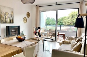 Ein modernes Wohnzimmer mit Essbereich, großen Fenstern und Blick ins Freie.