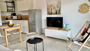 A modern kitchen with white cabinets, a stainless steel refrigerator, a microwave, and a dining area with a table and chairs. - The Ondella T2 in Porticcio with a garage (Grosseto-Prugna)