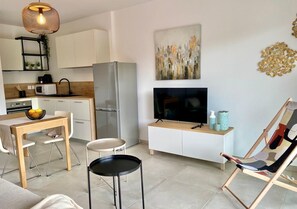 A modern kitchen with white cabinets, a stainless steel refrigerator, a microwave, and a dining area with a table and chairs. - The Ondella T2 in Porticcio with a garage (Grosseto-Prugna)