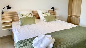 A bedroom with a bed, two bedside lamps, a wooden headboard, and a closet with wooden hangers. - The Ondella T2 in Porticcio with a garage (Grosseto-Prugna)