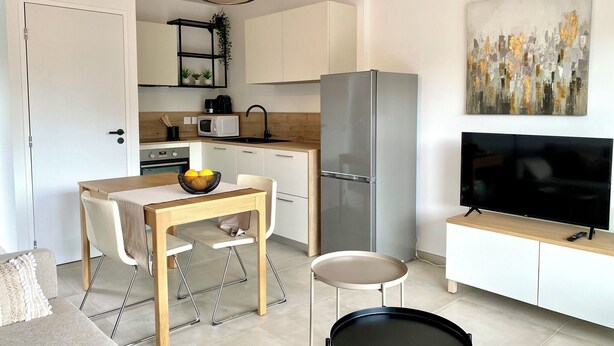 A modern kitchen with a dining area, a refrigerator, a microwave, a sink, and a television. - The Ondella T2 in Porticcio with a garage (Grosseto-Prugna)