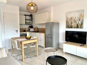 Eine moderne Küche mit Essbereich, einem Kühlschrank, einer Mikrowelle, einem Spülbecken und einem Fernseher.