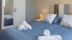 Et soveværelse med seng, et natbord, en lampe, et garderobeskab og et spejl.