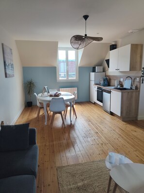 A compact living space with a dining area, kitchenette, and a ceiling fan. - Écume and Horizon—3-bedroom apartment for up to 4 people—Beach 100 meters away—Ocean view from the living room (Ault)