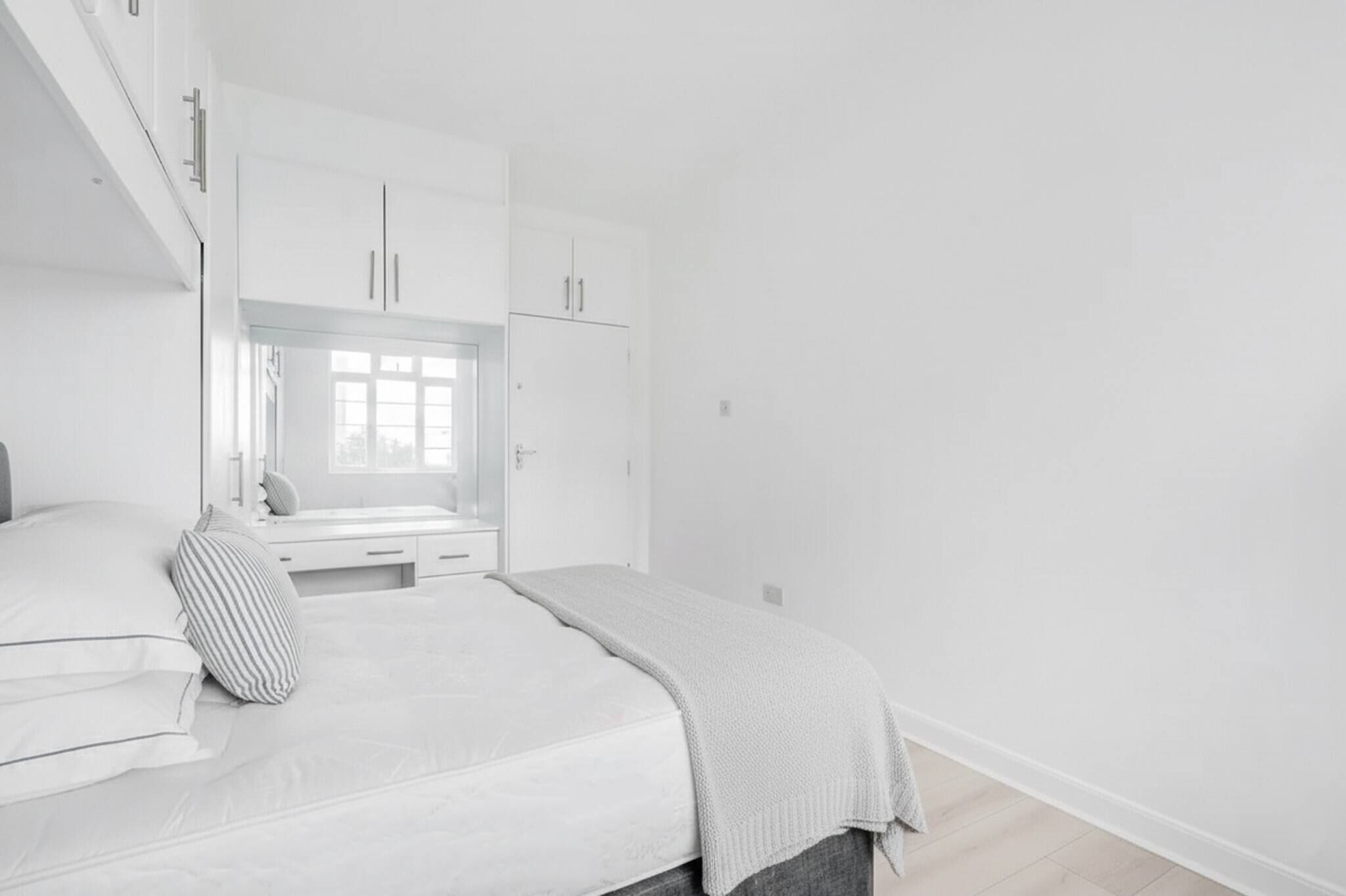 Un dormitorio con cama, ventana y armarios empotrados.