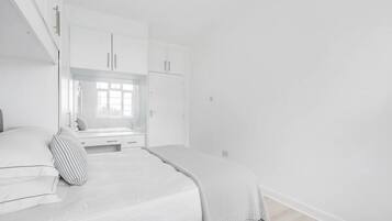 Un dormitorio con cama, ventana y armarios empotrados.