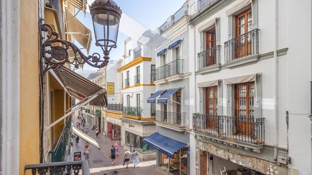 Una calle estrecha con edificios, balcones y una escalera.