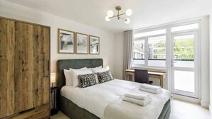Quarto com cama, escrivaninha, guarda-roupa e janela com vista.
