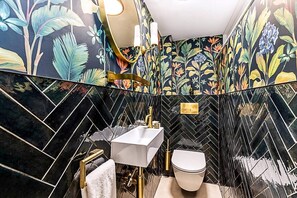 A bathroom with a herringbone tile pattern, a white sink, a gold faucet, and a toilet. - Soho 3bedroom Entire Flat - Spacious Sleeps 10 (London)